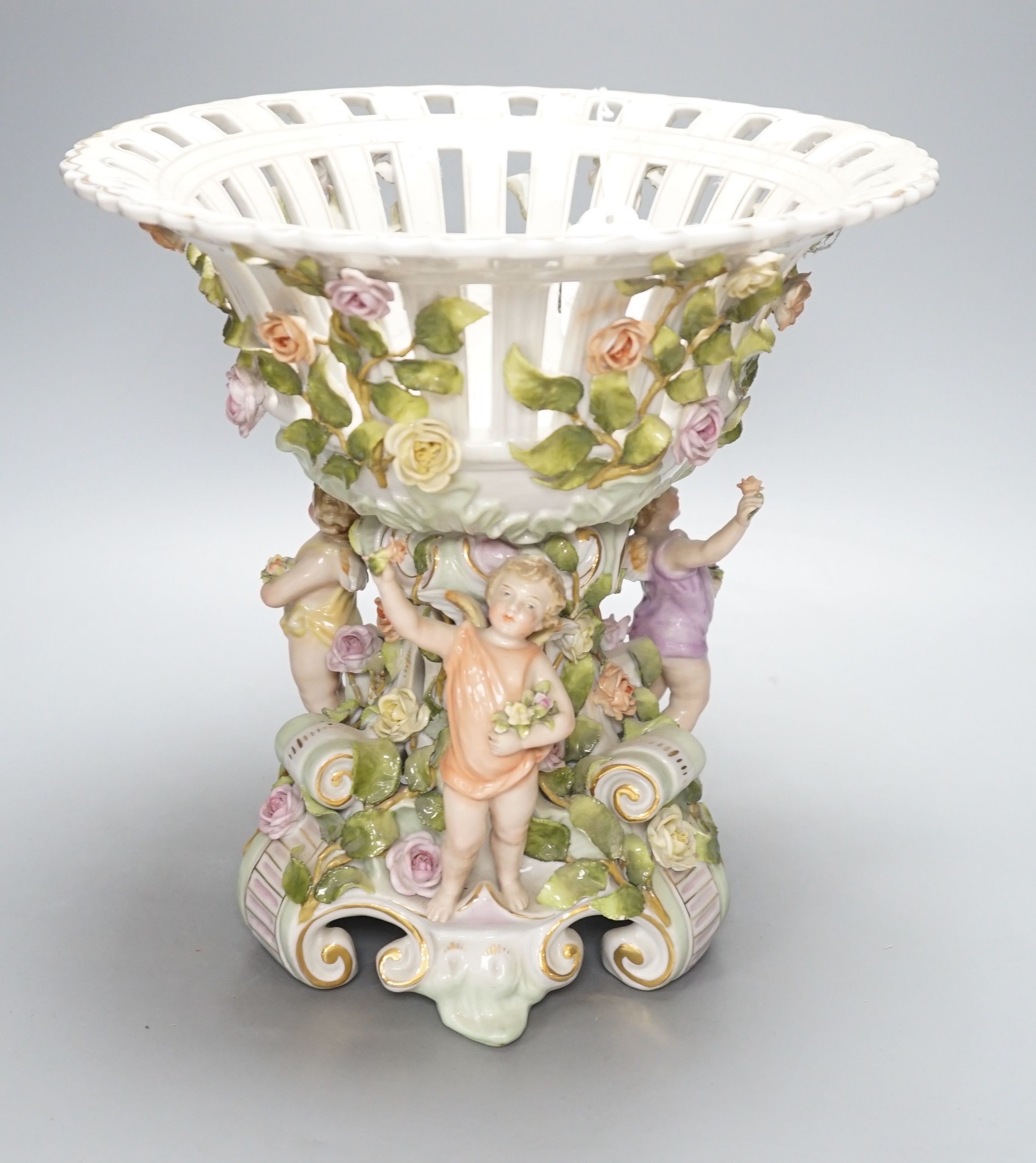 A German porcelain floral encrusted fruit stand, on a figural base, 30cm tall